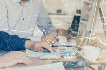 Multi exposure of chart with man typing on computer in office on background. Concept of hard work.