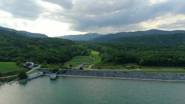 Lake Butoniga freshwater reservoir in Croatia approaching dam wall on an overcast day, Aerial drone flyover shot