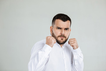 Fototapeta premium portrait of angry bearded man with fists raised ready to fight on gray background.