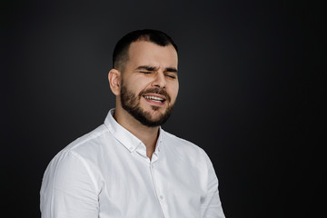 Obraz premium Close-up portrait of happy handsome bearded man laughing on black background