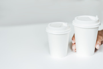 Mockup of famale hand holding a Coffee paper cup isolated on light grey background