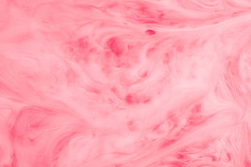 A macro photo of drops of red food dye swirled and mixed into thick creamy white milk to give a...