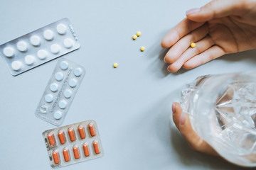 Hands holding the tablets with  glass of water. Tablets in packs. Tablets on a light background. Different types of pills. 