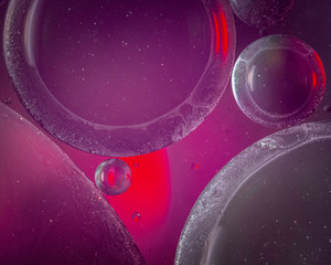 An abstract artistic close up macro photo created by mixing oil and water then back lit with a red and purple flash