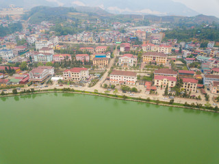 Fototapeta na wymiar Aerial view of Sapa cityscape covered by fog with Sapa lake an iconic emerald green lake in the downtown of Sapa the capital city in Lao Cai province in north-west of Vietnam.