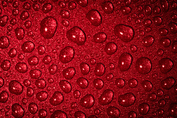 A close up abstract macro photo of water droplets on a grey non stick frying pan material lit with a red flash gel