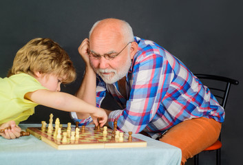 Chess competition. Grandpa and grandson playing chess spending free time together. Grandfather and grandson playing chess. Brain development and logic concept. Kid boy playing chess with grandfather.