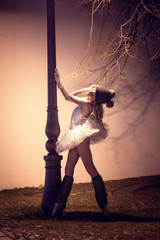 Tänzerin posiert an eine Strassenlaterne nachts auf Spoitzenschuhen