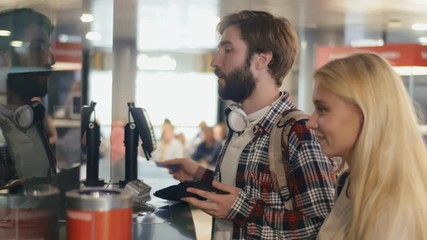 Woman and a man with are buying plane tickets at ticket service