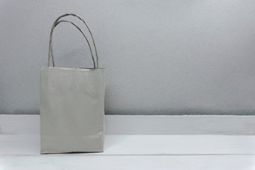One Blank brown paper carrier bag with handles for shopping on wood white table With copy space on...
