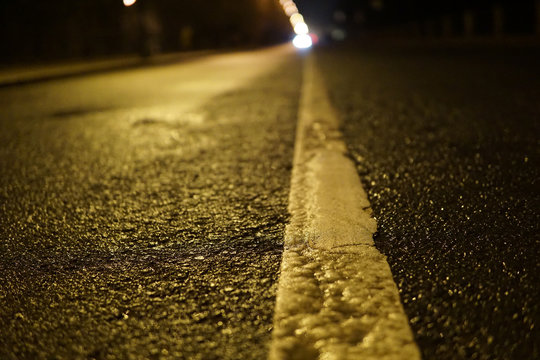 Separation line on the asphalt. Night road. Macro view.