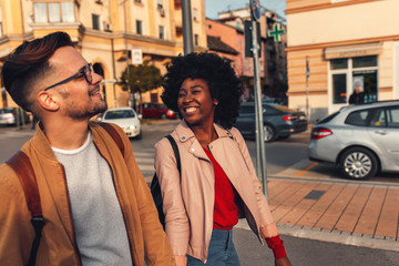 Smiling couple enjoying on vacation, young tourist having fun walking and exploring city street during the day.