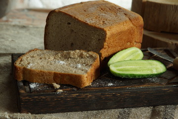 Still life with mouth-watering fresh bread and salt, next to a fresh cucumber from a vegetable garden in a village, rustic style