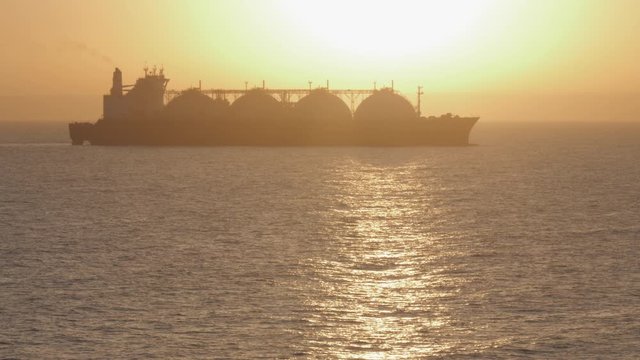 Large LNG tanker heading at sea in sun back light