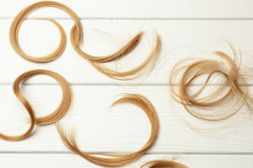 Cut hair curls on a white wooden background
