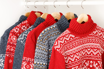 Collection of knitted Christmas turtleneck sweaters on hanger rack in a  wardrobe