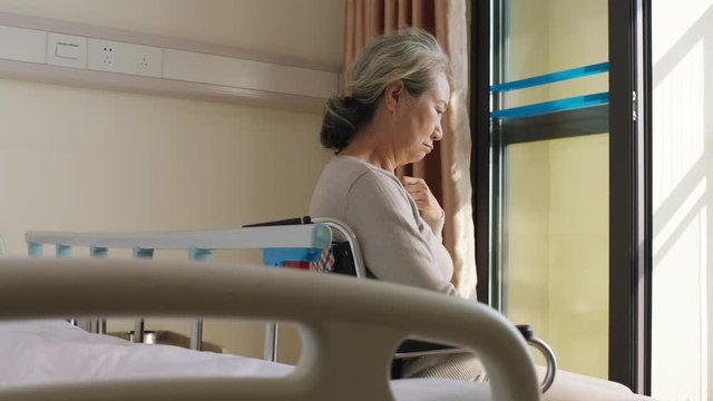 asian old woman sitting in wheel chair alone in her room in nursing home