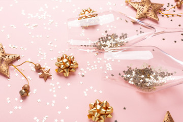 Fototapeta na wymiar Christmas flat lay. Champagne glasses and gold decoration on pink background