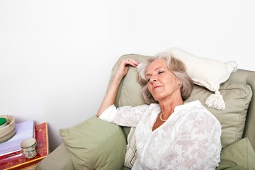 Tired senior woman sleeping on armchair at home