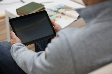 Male hand holds tablet in home setting while