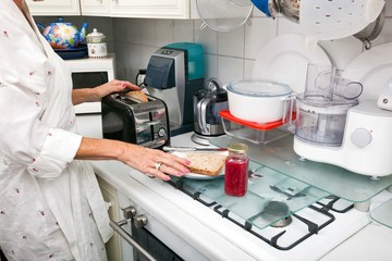 Midsection of senior woman preparing toast at kitchen counter