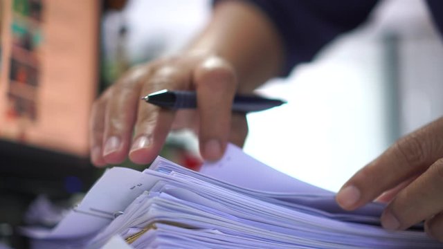 Businessman hands working in stacks of paper files for searching information on work desk office, business report papers,piles of unfinished documents achieves with clips indoor,Business concept