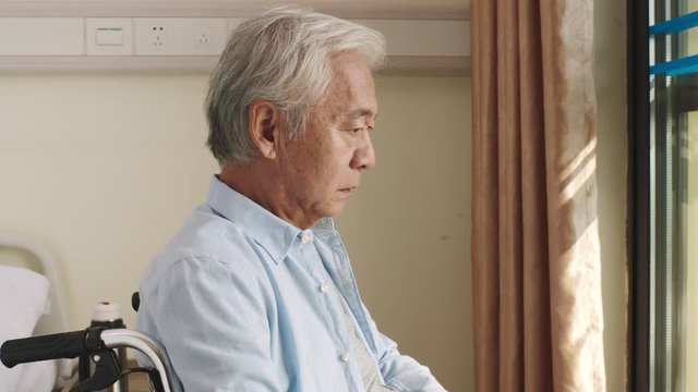 asian old man sitting in wheel chair alone in his room in nursing home