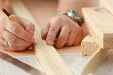 Arms of worker measuring wooden bar
