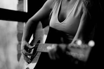 Obraz premium girl plays the guitar near the window in a white T-shirt black and white