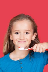 Portrait of girl holding toothbrush against red background