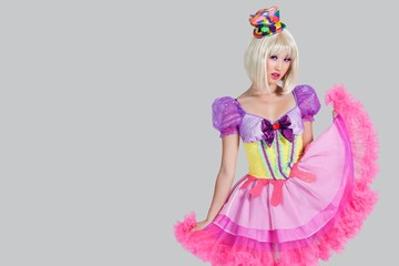 Portrait of young woman in doll's costume posing against gray background