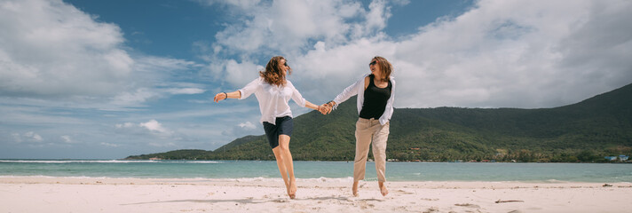 A pair of girls in love have fun running around on a tropical beach.