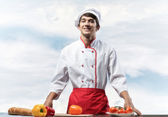 Young male chef standing near cooking table