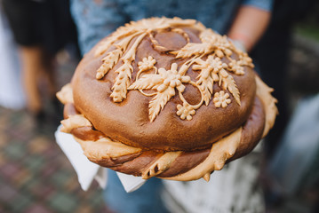 Wedding loaf with Ukrainian and Russian traditions in the hands of close-up. Tasty, round,...