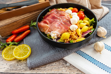 Salad made with cooked pasta, mixed green salads, cherry tomatoes, Mozzarella cheese and smoked ham...