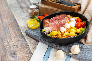 Salad made with cooked pasta, mixed green salads, cherry tomatoes, Mozzarella cheese and smoked ham served with accompaniment