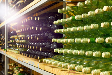 Horizontal rows of red and white wine bottles on the shelf in a cellar. Close up