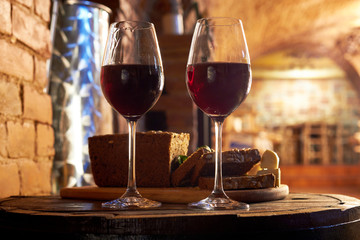 Two glasses of red wine, few pieces of rye bread, cheese and basil