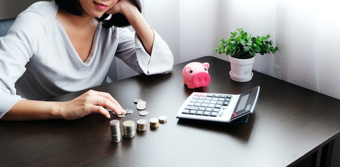 Asian women counting coins and pressing the calculator to calculate the money received from the...