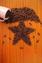 Obraz na płótnie Canvas Christmas Greeting Card Background With Coffee Beans. Vertical picture of spilled coffee beans from the pink ceramic mug forming a star shape on a wooden table.