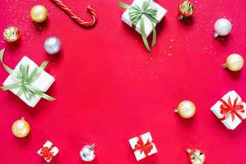 Chrismas balls, christmas gifts and caramel cane isolated on red background. Concept of Christmas and new year.