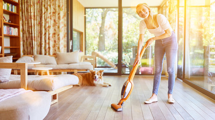 Frau mit Staubsauger und Hund im Wohnzimmer