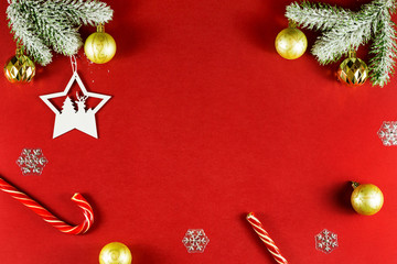 Snowy sprigs of pine, caramel cane, chrismas balls and snowflakes isolated on red background. Copy space for your text.