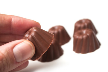 Closeup of hand of man taking a Chocolate in shaped kouglof on white background