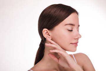 Side view of calm peaceful young woman posing on camera. Portrait of model touch face with fingers....