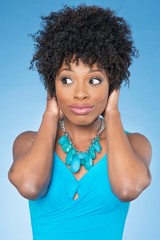 Happy African American woman covering ears over while looking away colored background