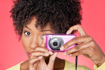 Portrait of an African American woman taking picture from camera over colored background