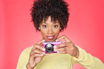 Portrait of an African American woman holding a camera over colored background