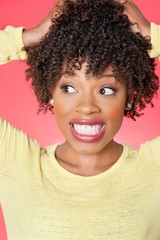 African American looking sideways with hands in hair over colored background