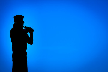 Soldier in silhouette holding binoculars.